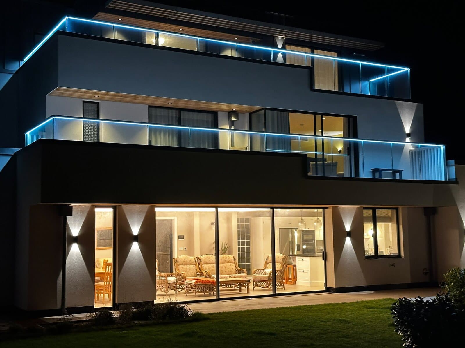 New build at night with LED strips along both glass balconies and up and down wall lights
