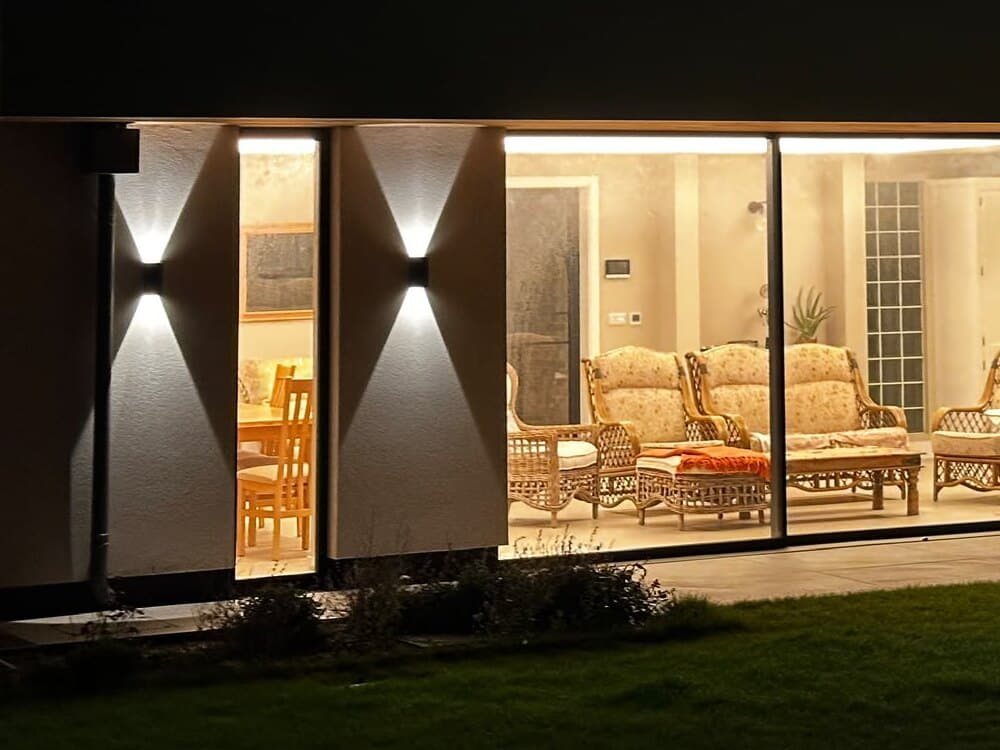 Up and down wall lights beside wide sliding glass doors onto the lawn